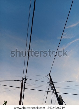 "Tiang listrik" electric pillars with lots of high voltage wires are located by the side of the road Royalty-Free Stock Photo #2436926719