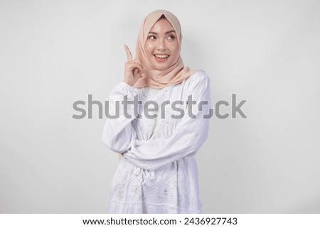 Thoughtful young Asian Muslim woman wearing white dress and hijab thinking and finding idea with happy expression, isolated on white background Royalty-Free Stock Photo #2436927743