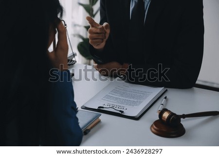 Justice and Law concept. Legal counsel presents to the client a signed contract with gavel and legal law or legal having team meeting at law firm in background