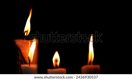 Light of the candles in the dark. Four candle lights burned in the night on black background. Candle lights backgrounds. Copy space.