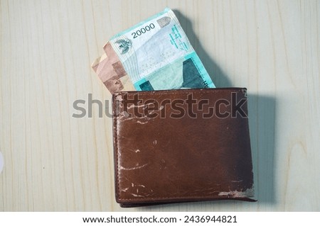 Rupiah banknote in brown wallet on wood background. Money photo concept.