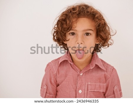 Boy, child and portrait in studio with tongue out for funny face, joke or games by white background. Kid, mouth and comic gesture with fashion, playful and emoji with trendy style, shirt or clothes