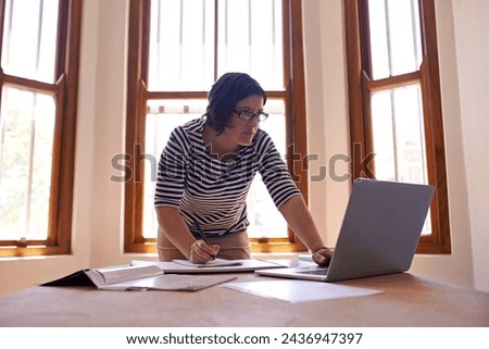 Businesswoman, laptop and notes at desk, office and technology for startup business owner. Entrepreneur, research and computer for female designer, writing and notebook for project in workplace