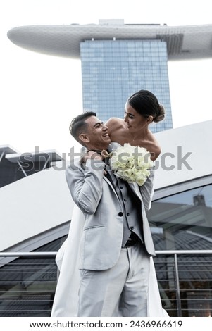 Positive family emotions.Bride and groom against the backdrop of the city of Singapore. Sunrise wedding photoshoot. The loving couple is laughing.The bride with a bouquet of white flowers.