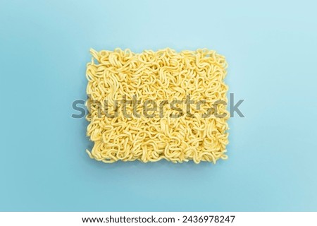 Instant noodles, raw, briquette on bright blue background color.