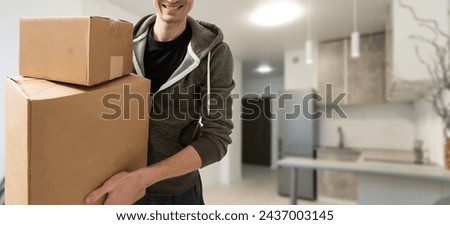 young man carries moving boxes