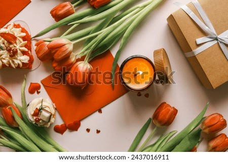 Beautiful spring background, burning candle, red tulips, gift box and cake.