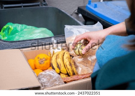 Food waste Close-up. Throwing away food, female hand throws vegetables, fruit, sausage and cornflakes into the garbage can. Still edible, not spoiled Royalty-Free Stock Photo #2437022351