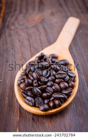 Coffee beans in wooden spoon on wood background - vintage effect style pictures