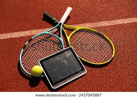 High angle view of tennis racket and ball by digital tablet on maroon background