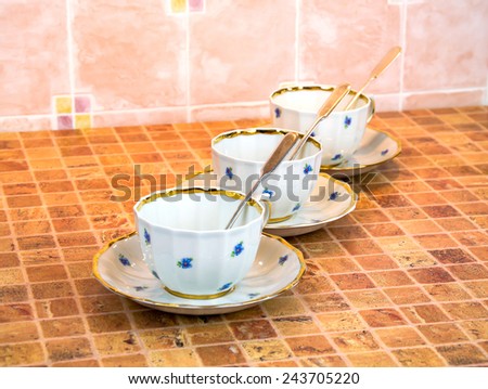 A chinese porcelain cups of tea with saucer and silver teaspoons are on the multicolor table
