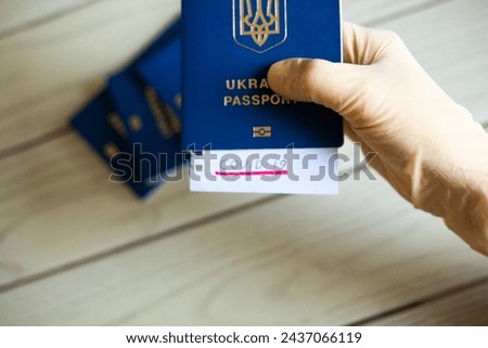 Hand in medical glove holding passport with Covid-19 note. Coronavirus disease outbreak. Travelling in epidemic period. Passport border control and quarantine of infected tourists. Royalty-Free Stock Photo #2437066119
