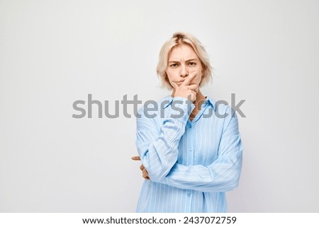 Confused young woman with hand on chin, looking uncertain, isolated on white background.