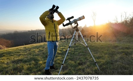 Amateur astronomer observing skies with binoculars and telescope. Royalty-Free Stock Photo #2437078735