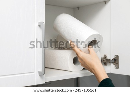 housewife takes out a roll of paper towel from the kitchen cabinet. paper towel in the closet. using a paper towel. High quality photo
