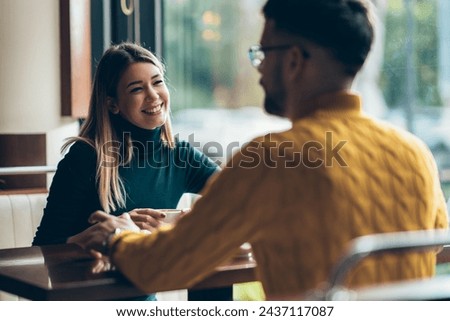beautiful young couple sitting in a cafe and enjoying time together Royalty-Free Stock Photo #2437117087