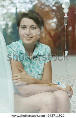 Smiling girl looking through the window in hospital