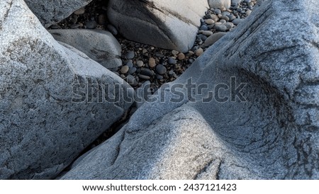 The Melted Rocks of Swamis Beach. Erosion control stone put down along the shore 50 years ago lies polished by ancient river rocks in the surf mix at Swamis Reef Surf Park Encinitas California.