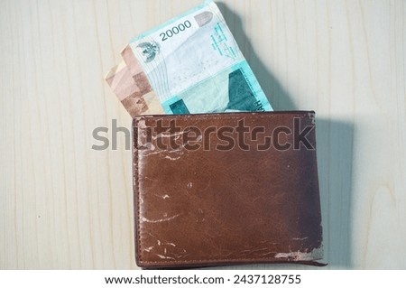 Rupiah banknote in brown wallet on wood background. Money photo concept.