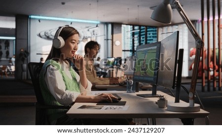 Female Asian Game Designer Using Desktop Computer, Designing Unique World And Characters In 3D modelling Software For RPG Video Game. Woman Working In Diverse Game Development Studio Office