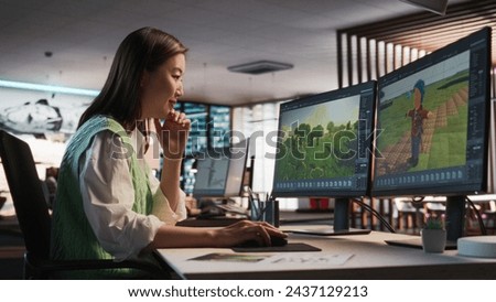 Female Asian Game Designer Using Desktop Computer, Designing Unique World And Characters In 3D modelling Software For RPG Video Game. Woman Working In Diverse Game Development Studio Office.
