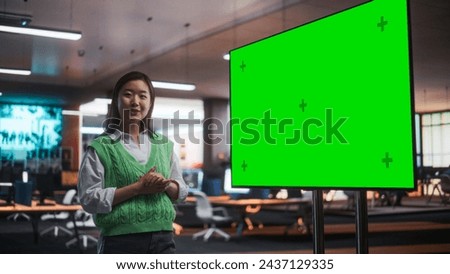 Creative Office Meeting: Portrait of Beautiful Asian Female Project Manager Presenting Goals For Marketing Strategy, Uses TV Set with Green Screen Mock Up