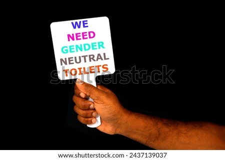 WE NEED GENDER NEUTRAL TOILETS Sign board showing by hand with black background close-up view, Protester holding a white board with writing we need gender neutral toilets 