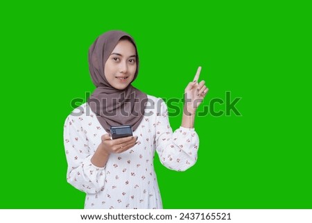 Asian Muslim woman carrying a phone while showing her finger isolated on green screen