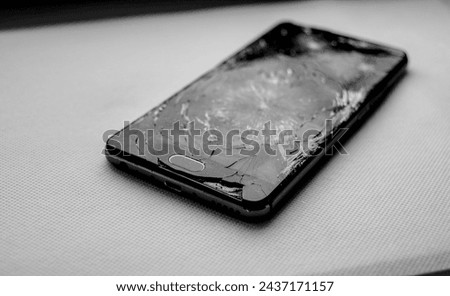 Modern smartphone with damaged glass screen isolated on white background. Device needs repair.