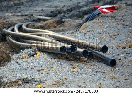 Laying of plastic communication pipes at the construction site of road repair works. A bundle of pipes sticking out of the ground.