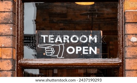 Brown Wooden framed window in brick wall with o;f fashione sign pointing towards a tearoom
