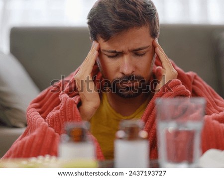 autumn and winter season of sneezes. Young Caucasian man with flu feels cold in living room at home, having fever and headache and touching his forehead to check his temperature.