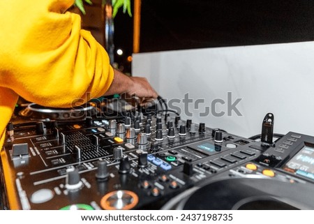 Deejay in yellow hoodie mixing music on audio equipment