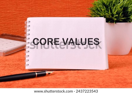 CORE VALUES word written on a blank sheet of notepad, there is a calculator, a pen and a flower in the background Royalty-Free Stock Photo #2437223543