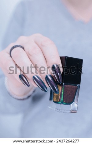 Woman's beautiful hand with long nails and dark blue black and brown manicure