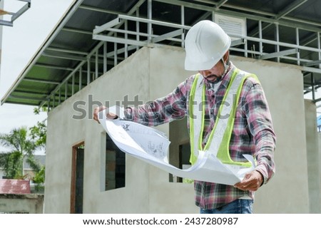 Man construction engineer wears helmet ensure safety when working in construction zone, standing on pile rocks, looking checking for completeness in case there is error so that it can be corrected. Royalty-Free Stock Photo #2437280987