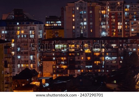 Front view of typical georgian multi storey apartment, residential buildings facade with warm illuminated windows and night lighting, illumination in Batumi, Georgia Royalty-Free Stock Photo #2437290701