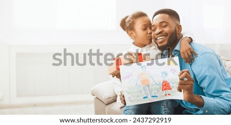 Little black girl hugging father, giving handmade drawing and present box, copy space