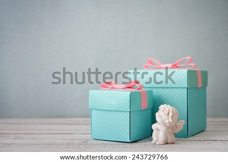 Blue polka dots gift boxes with statuette of angel on wooden background