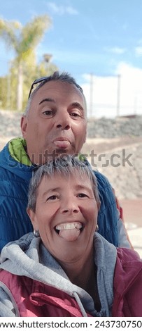 Happy couple taking a selfie with their tongues hanging out. Fun afternoon between two lovers.