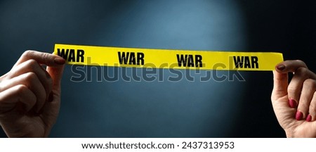 Hands Holding Yellow Tape With War Text On Black Background