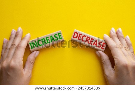 Increase or Decrease symbol. Concept word Increase or Decrease on wooden blocks. Businessman hand. Beautiful yellow background. Business and Increase or Decrease concept. Copy space Royalty-Free Stock Photo #2437314539