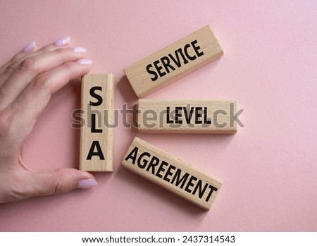 SLA - Service Level Agreement. Wooden blocks with word SLA. Businessman hand. Beautiful pink background. Business and Service Level Agreement concept. Copy space.