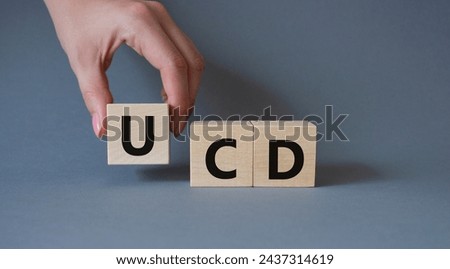 UCD - User Centered Design. Wooden cubes with word UCD. Businessman hand. Beautiful grey background. Business and User Centered Design concept. Copy space.