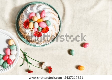 Easter cake decorated with icing sugar, small colorful chocolate eggs and daisy flowers. Traditional easter cake or sweet bread with topping. Easter treat. Royalty-Free Stock Photo #2437317821