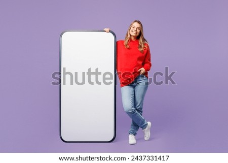 Full body smiling happy young blonde woman wears red hoody casual clothes big huge blank screen mobile cell phone smartphone with workspace copy space mockup area isolated on plain purple background