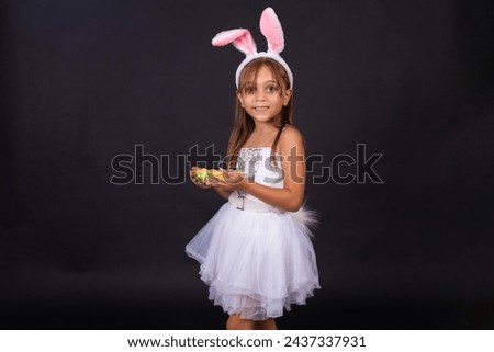 Cute little girl wearing bunny ears on Easter day. Girl holding basket with painted eggs. Royalty-Free Stock Photo #2437337931