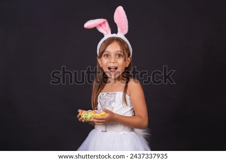Cute little girl wearing bunny ears on Easter day. Girl holding basket with painted eggs. Royalty-Free Stock Photo #2437337935
