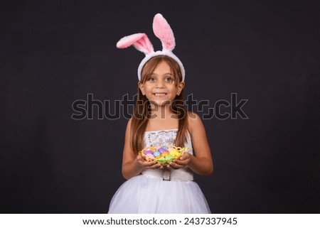 Cute little girl wearing bunny ears on Easter day. Girl holding basket with painted eggs. Royalty-Free Stock Photo #2437337945