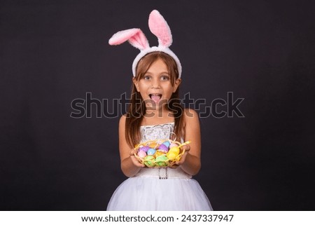 Cute little girl wearing bunny ears on Easter day. Girl holding basket with painted eggs. Royalty-Free Stock Photo #2437337947